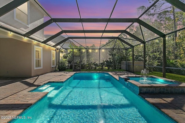 pool at dusk with pool water feature, an in ground hot tub, a patio area, and a lanai