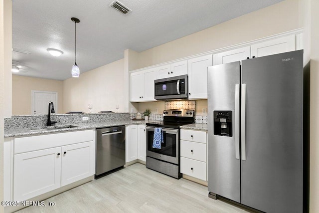 kitchen featuring appliances with stainless steel finishes, decorative light fixtures, white cabinetry, sink, and decorative backsplash