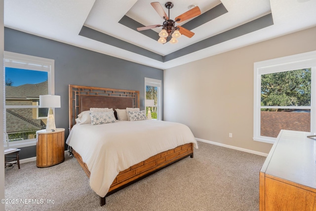 bedroom with a tray ceiling, ceiling fan, and carpet