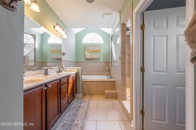 bathroom with tile patterned floors, vanity, separate shower and tub, and vaulted ceiling