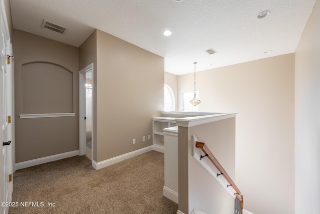 hallway with light colored carpet and a textured ceiling