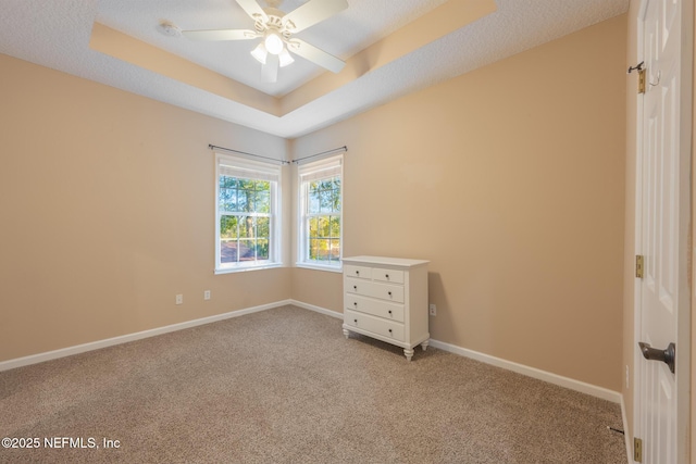 unfurnished bedroom featuring ceiling fan, a raised ceiling, light colored carpet, and a textured ceiling