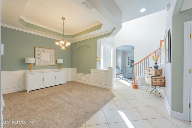 dining space with ceiling fan with notable chandelier, a raised ceiling, ornamental molding, and light tile patterned floors