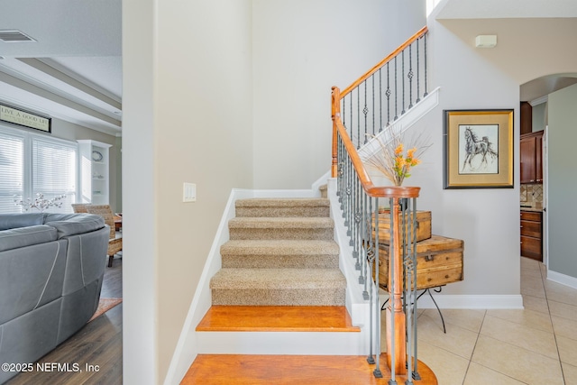 stairway featuring tile patterned floors and a tray ceiling