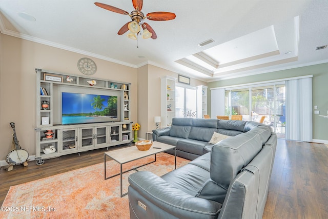 living room with hardwood / wood-style floors, a raised ceiling, ceiling fan, and ornamental molding