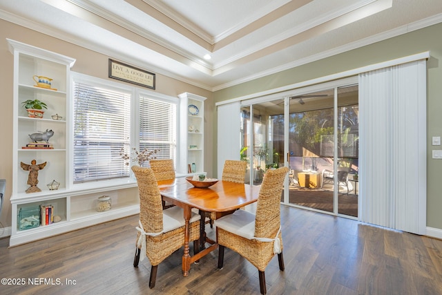 dining space featuring built in shelves, dark hardwood / wood-style floors, a raised ceiling, and crown molding