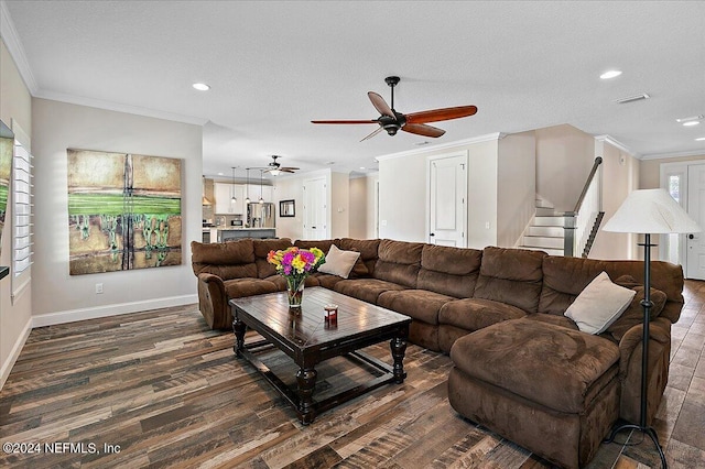 living room with a textured ceiling, crown molding, ceiling fan, and dark wood-type flooring