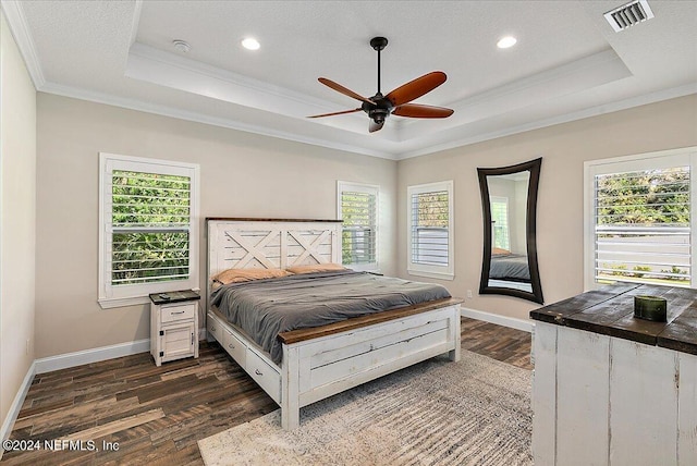 bedroom featuring dark wood-type flooring, a raised ceiling, ceiling fan, and crown molding