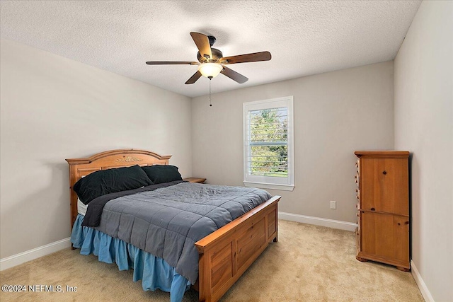 bedroom with a textured ceiling, light colored carpet, and ceiling fan