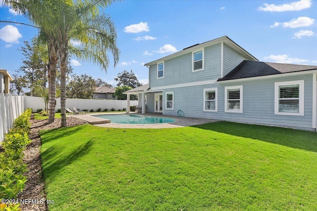 back of property with a fenced in pool and a yard