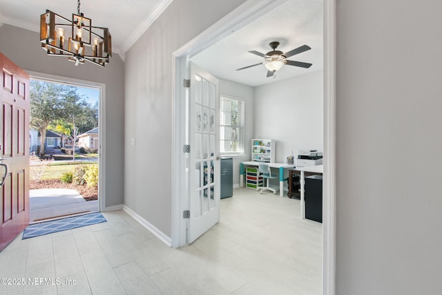 entryway with ceiling fan with notable chandelier, a healthy amount of sunlight, crown molding, and french doors