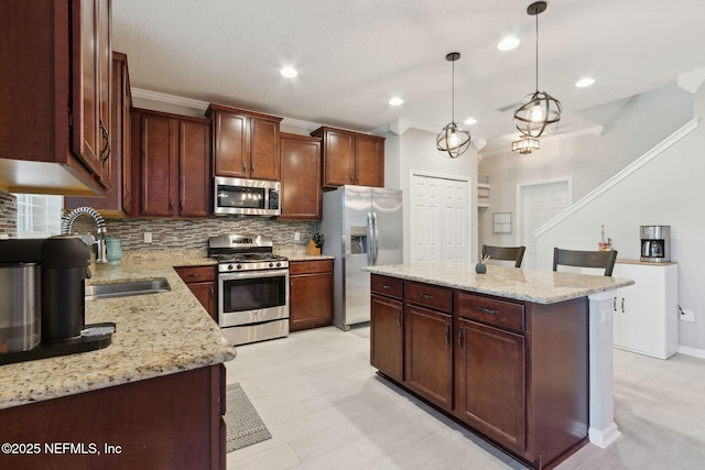 kitchen featuring sink, decorative backsplash, appliances with stainless steel finishes, decorative light fixtures, and a kitchen island