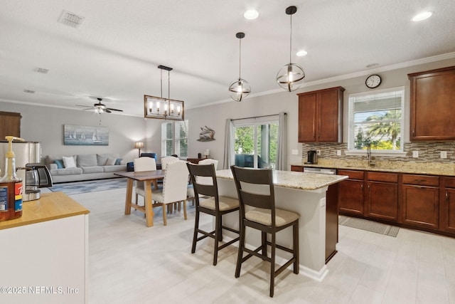 kitchen featuring light stone countertops, a kitchen breakfast bar, tasteful backsplash, ceiling fan, and decorative light fixtures