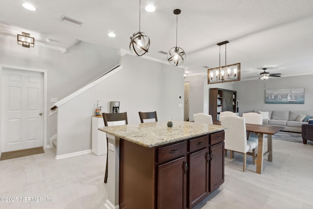 kitchen featuring a kitchen breakfast bar, a center island, hanging light fixtures, and ornamental molding