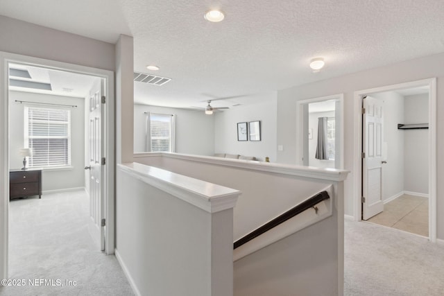 hall featuring a textured ceiling and light carpet