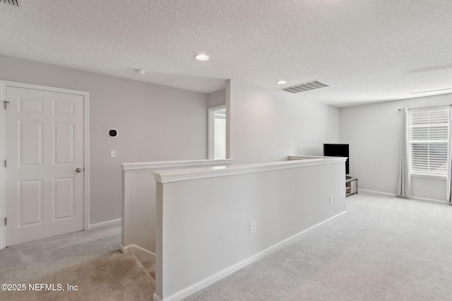 corridor featuring light carpet and a textured ceiling