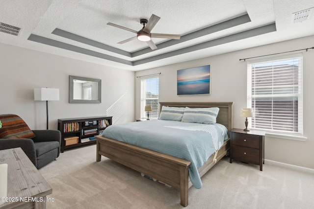 carpeted bedroom with a textured ceiling, a raised ceiling, and ceiling fan