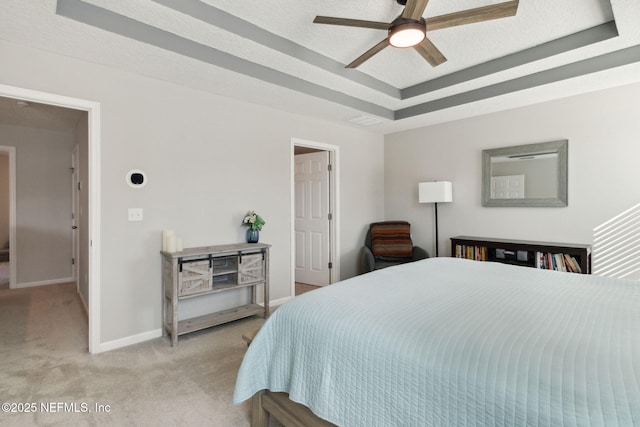 carpeted bedroom featuring a textured ceiling, a tray ceiling, and ceiling fan