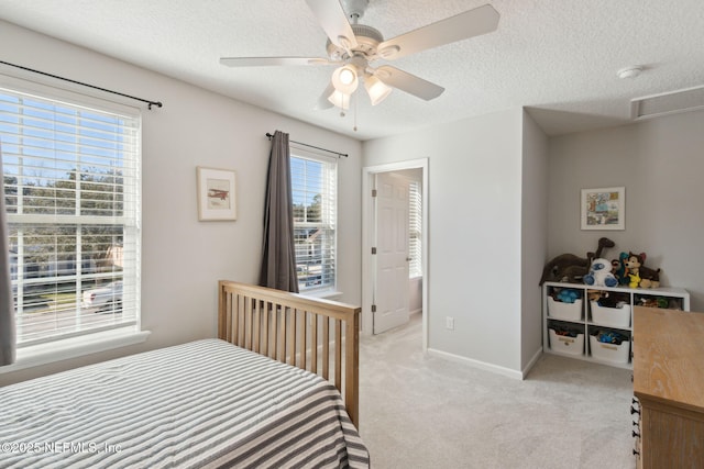 bedroom with a textured ceiling, ceiling fan, and light carpet