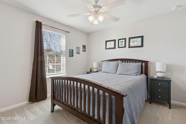 bedroom with ceiling fan, light colored carpet, and a textured ceiling