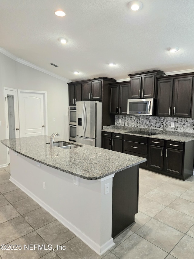 kitchen with a kitchen island with sink, sink, decorative backsplash, ornamental molding, and stainless steel appliances