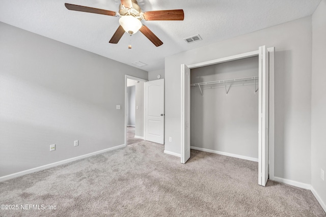 unfurnished bedroom featuring a textured ceiling, a closet, light colored carpet, and ceiling fan