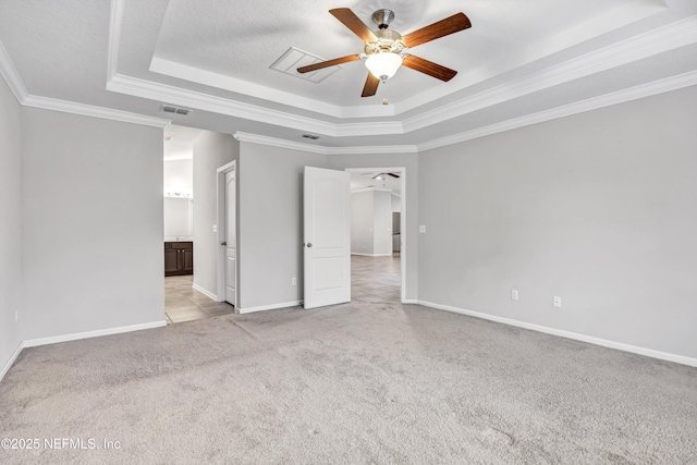 empty room with a tray ceiling, ceiling fan, crown molding, and light colored carpet