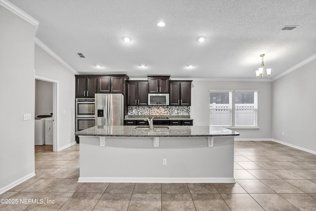 kitchen featuring sink, stainless steel appliances, washing machine and dryer, dark brown cabinets, and light tile patterned floors