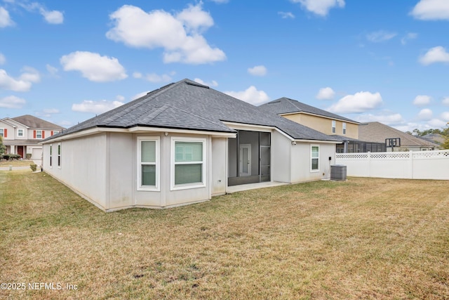 back of house with central AC unit, a sunroom, and a lawn