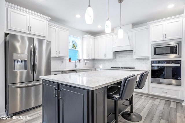 kitchen featuring white cabinets, light stone countertops, a kitchen island, and stainless steel appliances