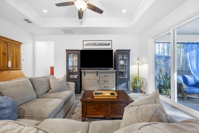 living room with a tray ceiling, ceiling fan, and ornamental molding