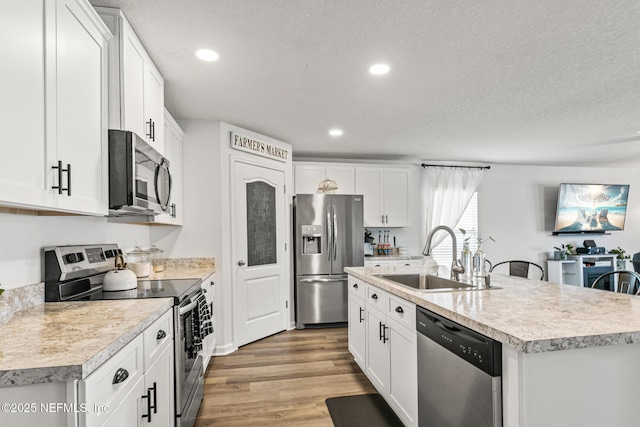 kitchen with a center island with sink, sink, white cabinetry, and stainless steel appliances