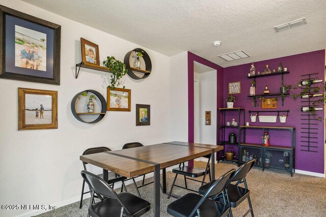 carpeted dining space with a textured ceiling