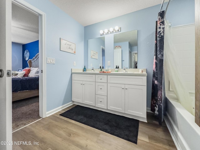 bathroom with vanity, hardwood / wood-style floors, a textured ceiling, and shower / bath combo with shower curtain