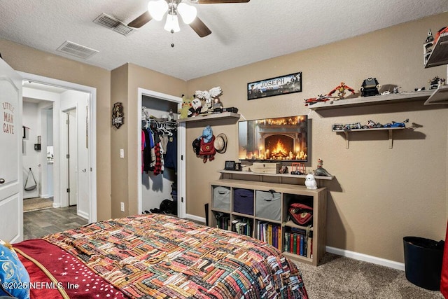 carpeted bedroom with ceiling fan, a closet, and a textured ceiling