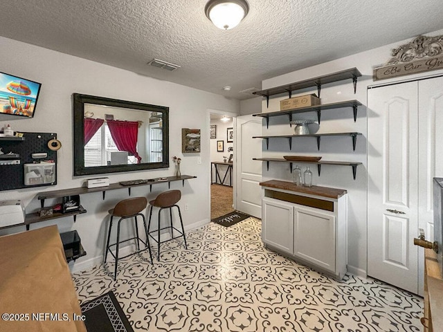 kitchen with a kitchen bar, gray cabinets, and a textured ceiling