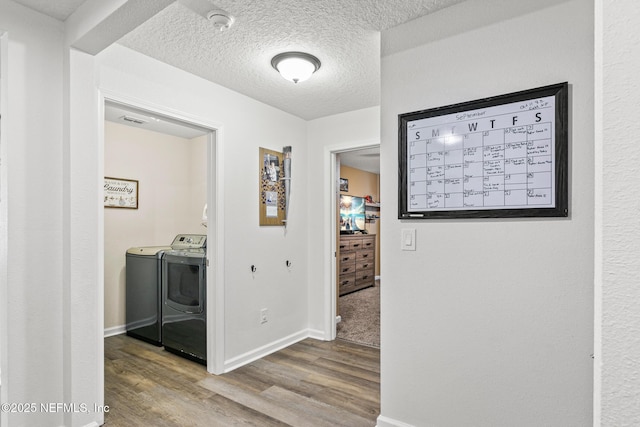 hallway featuring washer and dryer, a textured ceiling, and hardwood / wood-style flooring