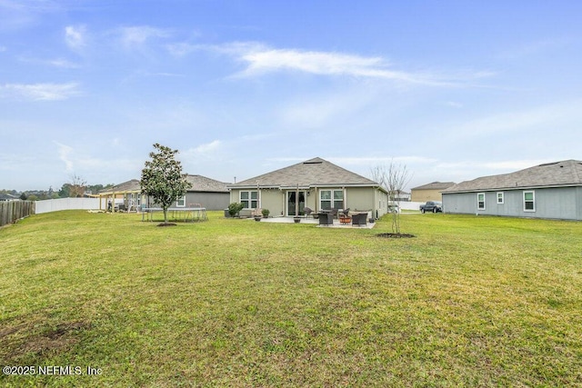 rear view of property with a yard, a patio, an outdoor hangout area, and a trampoline