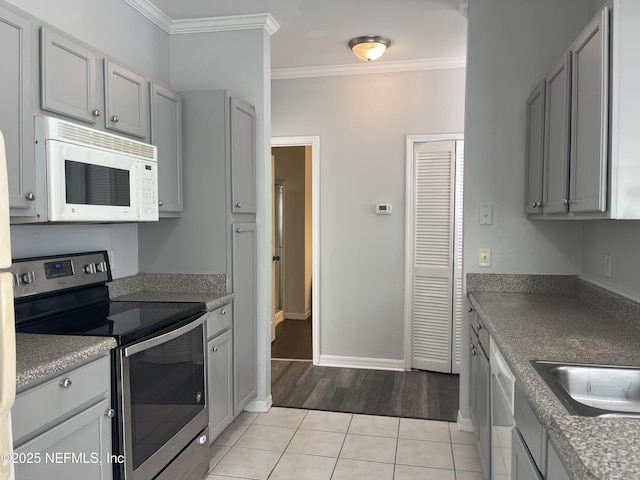 kitchen featuring gray cabinetry, white appliances, ornamental molding, and light tile patterned flooring