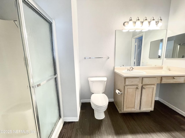 bathroom with hardwood / wood-style flooring, vanity, toilet, and a shower with shower door