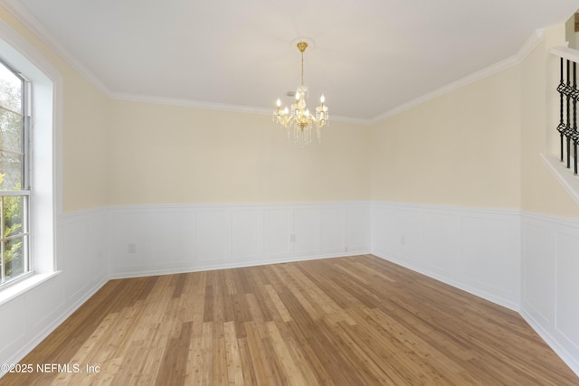 spare room with light hardwood / wood-style flooring, a chandelier, and ornamental molding