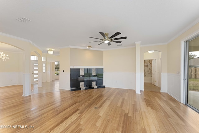 unfurnished living room featuring ceiling fan with notable chandelier, crown molding, and light hardwood / wood-style flooring