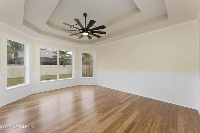 unfurnished room with hardwood / wood-style flooring, a raised ceiling, ceiling fan, and ornamental molding