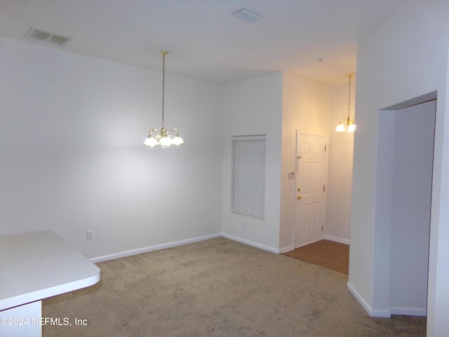 carpeted spare room featuring a notable chandelier