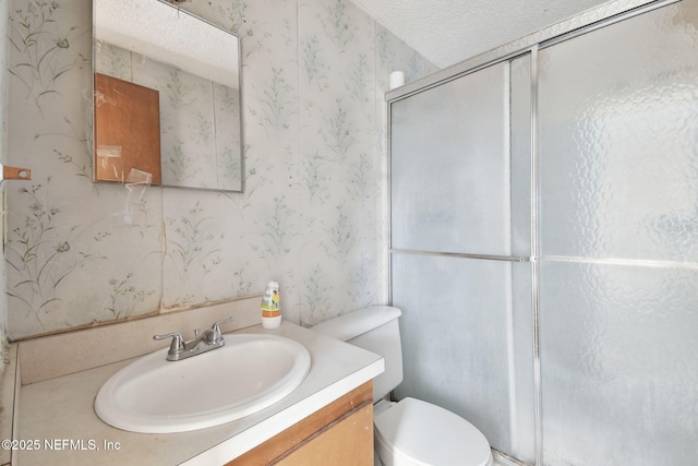 bathroom with vanity, a shower with shower door, a textured ceiling, and toilet