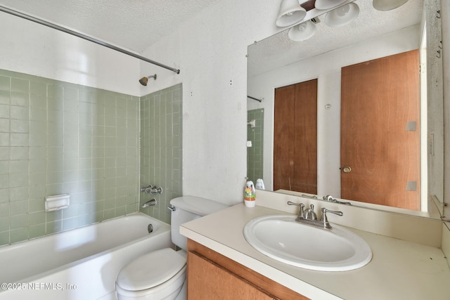 full bathroom with vanity, toilet, a textured ceiling, and tiled shower / bath