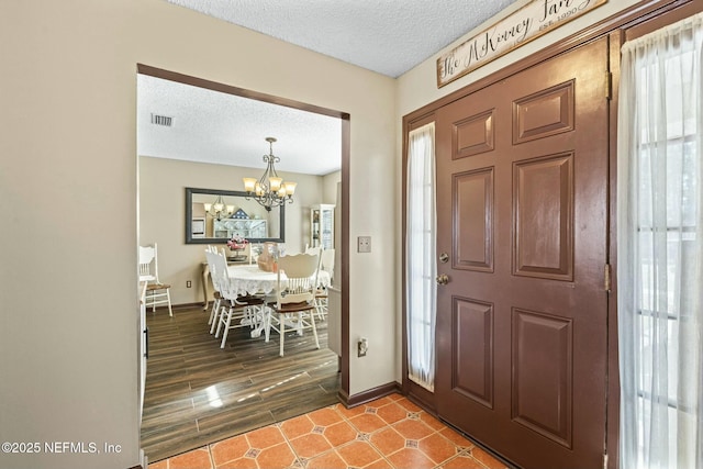 entryway with a chandelier and a textured ceiling