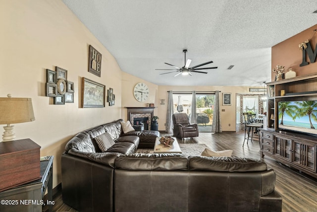 living room with ceiling fan, a textured ceiling, and a fireplace