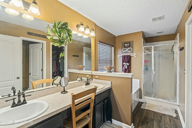 bathroom featuring plus walk in shower, a textured ceiling, and vanity