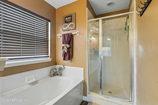 bathroom featuring a textured ceiling and shower with separate bathtub